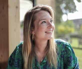 Een vrouw zit aan een tafel met een kop koffie.