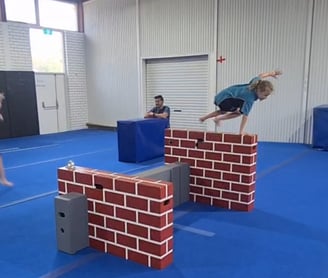 a person jumping over a brick wall