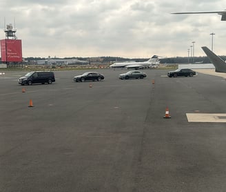 a plane is parked on the runway at an airport with cars driving towards it