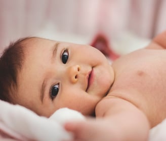 a baby laying and smiling.