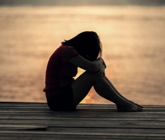 a sad girl sitting on near sea