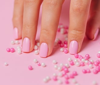 a hand with pink nail paint and some pearls