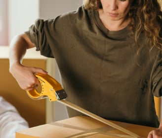 a women packing box with tape