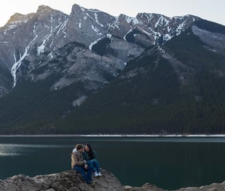 a couple sitting on a rock formation at lake minnewanka in Banff 