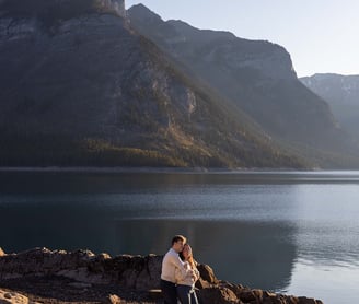 a man and woman standing on rocks in front of a mountain