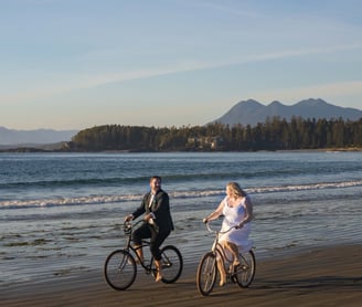 Bride and groom riding bikes on a beach in toxin during their elopement 