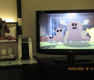 Girl sitting on a bed in the mirror watching cartoons