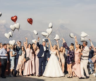 Grupowe zdjęcie pary młodej z gośćmi trzymającymi balony