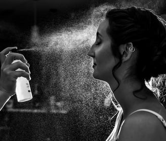 a woman is spraying makeup setting spray for a polished look