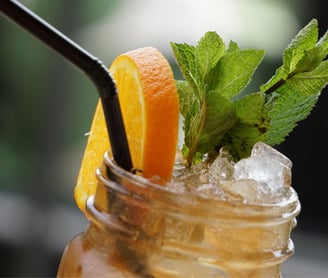 a drink in a mason jar with a strawberries and oranges