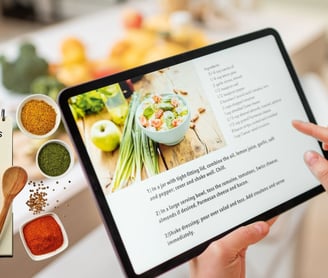 a person holding a tablet with a recipe book on it