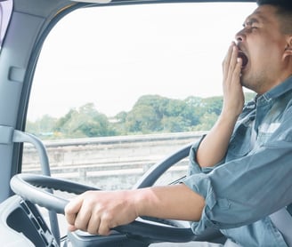 a man in a blue shirt is sitting in a truck yawning
