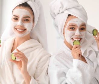 Two women with face masks and cucumber slices enjoying a spa day at home