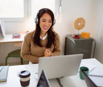 a woman with headphones at a laptop, engaged in an intensive language course with her tutor