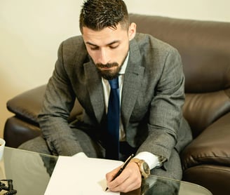 un hombre con traje y corbata escribe en un papel