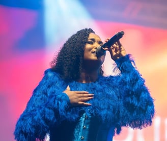 Fanny J portant une combinaison bleue roi effet plume signée Anais Ricard