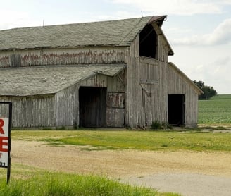a barn with a for sale sign in front of a barn