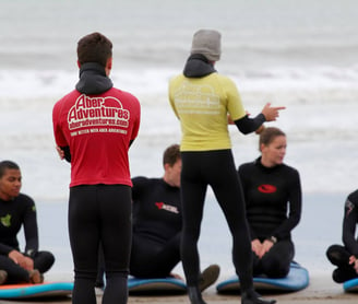 two surf coaches giving a safety brief while group listens.