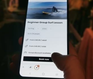 A mobile phone displaying a booking page someone clicking book now