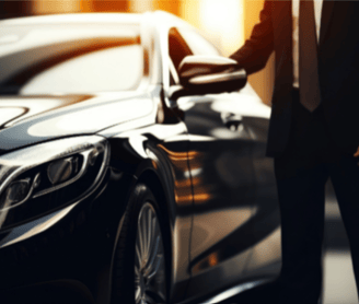 a private driver in a suit and tie standing next to a car