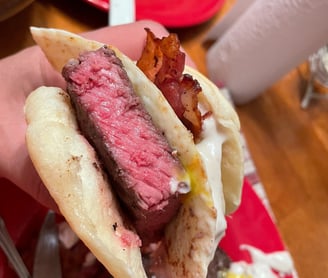 Rare steak served on a biscuit with egg and bacon