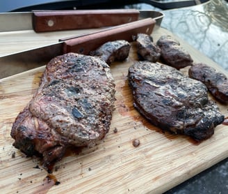 Ribeye and new york strip steaks cooked over coals caveman style