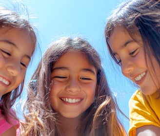 Fotografía de 3 niñas riéndose observando hacia el suelo 