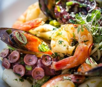 um prato de comida com camarão, camarão e legumes