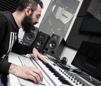 a man in a black shirt is playing a midi keyboard producing music in a studio lebanon