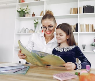 Profesora enseñando un libro a una niña
