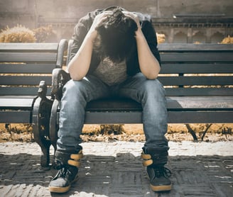 man sitting on a bench stressed out.  man is autism masking