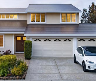 House with Tesla Solar Roof and White Tesla Electric Car parked in driveway