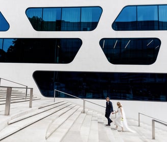 a bride and groom walking down stairs in front of a large building