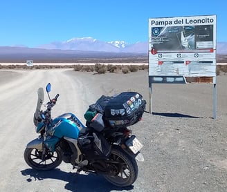 a motorcycle parked on a dirt road near a sign