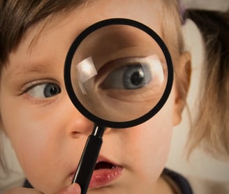 Criança observando curiosa pela lente o mundo: