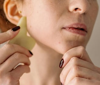 A woman using a gua sha as part of her regular step-by-step skincare routine