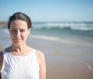 A happy woman by the beach dressed in white