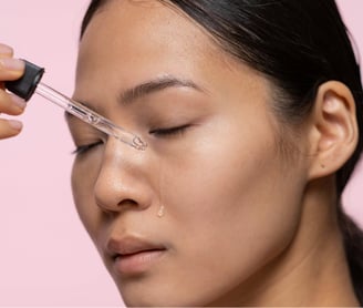 Asian woman applying serum on her face