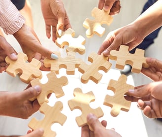 Hands holding wooden puzzle pieces – a symbol of teamwork and innovation of our company