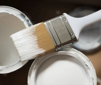 se está utilizando una brocha para pintar un bote de pintura blanca