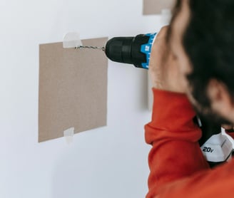 un hombre utiliza un taladro para instalar un muro