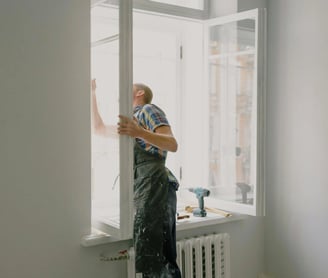 un hombre con mono de trabajo está pintando una ventana
