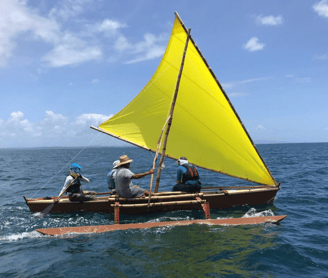 a group of people on a traditional style boat on the water in the Pacific
