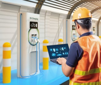 a man in a hard hat and safety vest holding a laptop fixing EV charger