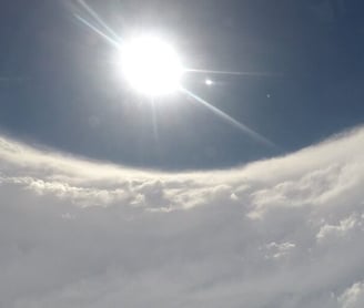 Hurricane Hunter flying in eye of hurricane looking out window, seeing plane engine and sun shinning about in clear eye.