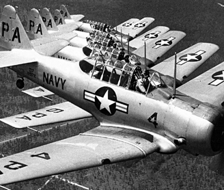 Group of six T-6 Texan aircraft flying in formation, US Navy paint scheme