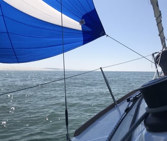 a sailboat sails through the water with a blue sky