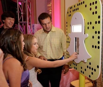 a man and woman standing in front of a snapchat logo phone booth