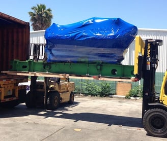 loading a large item with a large blue tarp into a truck 