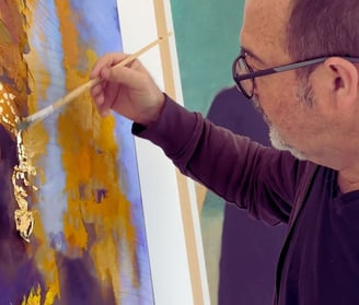 Martin Osner applying gold leaf to a mixed media artwork in his studio